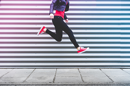 Young Happy Woman Jumping in Front of Metal Wall thumbnail