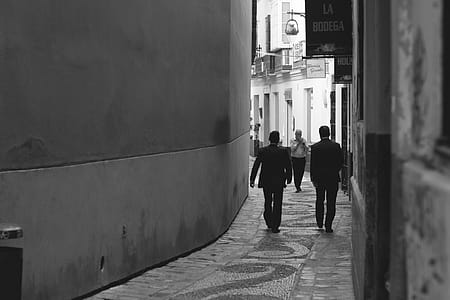 Grayscale Photo of Men Walking Near Wall thumbnail