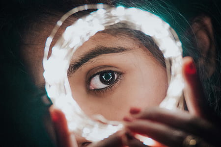 selective photography of woman's eye on center of white string light thumbnail