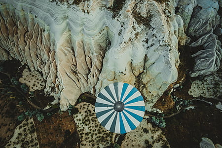 white and blue umbrella near brown rock thumbnail