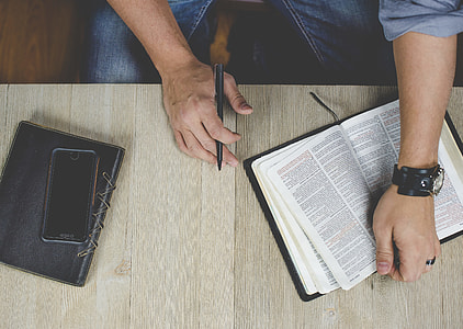 person holding book and pen thumbnail