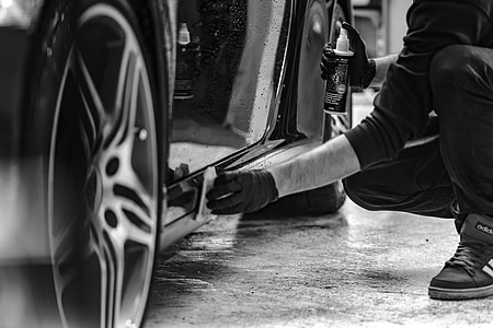 grayscale photography of man cleaning side skirts of car thumbnail