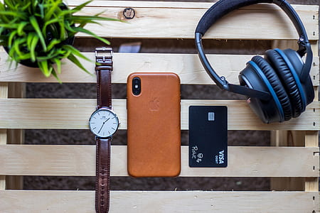 black and blue headphones near space gray iPhone X and brown leather case and round silver-colored analog watch thumbnail