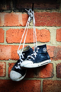 pair of sneakers hanging on brick wall thumbnail