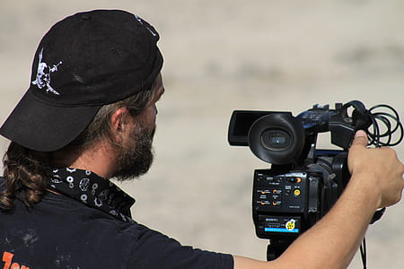 photo of man wears black cap holding black camera during daytime thumbnail