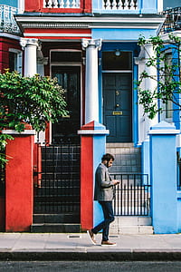 man walking front of blue and red house thumbnail
