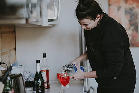 woman pouring drink on drinking glass in the kitchen thumbnail