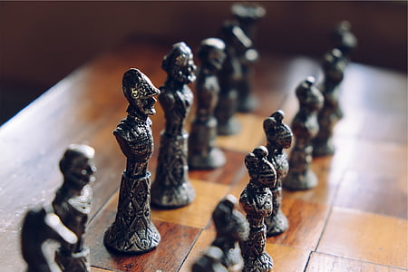selective focus on gray chess piece lot on brown wooden checkered board thumbnail