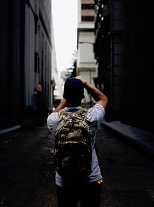 selective focus photography of man standing between concrete building at daytime thumbnail