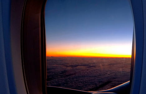 Photo of Airplane Window With View of Clouds and Golden Hour thumbnail