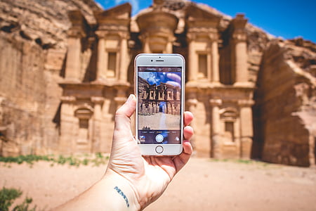 person holding gold iPhone 6 near beige concrete sculpture at daytime thumbnail