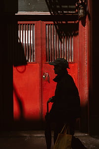person in front of red wooden door thumbnail