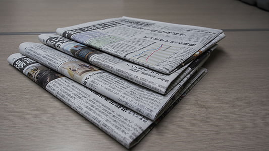 four newspapers on beige wooden surface thumbnail