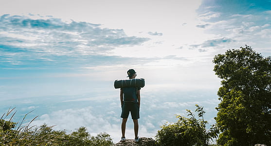 man carrying bag standing on cliff viewing clouds thumbnail