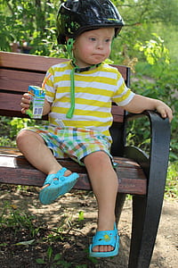 boy sitting on park bench while holding carton near plants thumbnail
