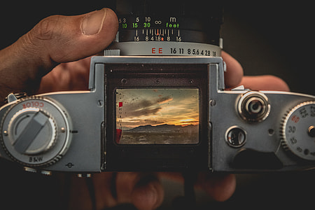 person holding silver camera thumbnail