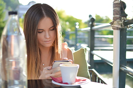 woman sitting on chair while holding phone thumbnail