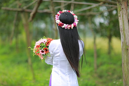 woman wearing flower crown, holding bouquet while standing thumbnail