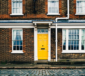Yellow entrance door on a brick home with white windows thumbnail