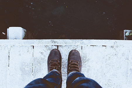 person wearing blue denim jeans and brown boots standing on white wooden dock thumbnail