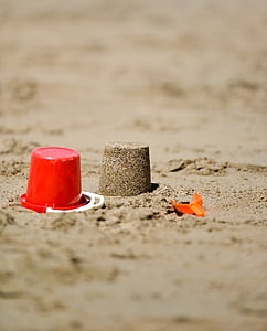 red sand bucket with shovel on seashore thumbnail
