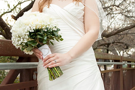 bride holding white petaled flower bouquet during daytime thumbnail