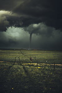 green grass field near tornado under cloudy sky thumbnail