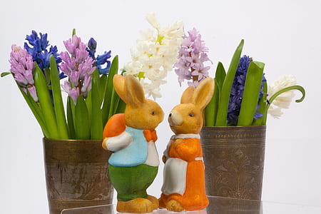 two brown rabbit figurines beside plants thumbnail