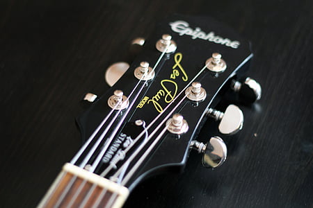 close-up photography of black and gray Epiphone guitar headstock on black wooden surface thumbnail
