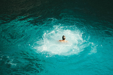 man swimming on green body of water thumbnail