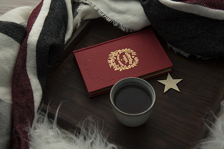 red book and gray cup filled with black liquid thumbnail