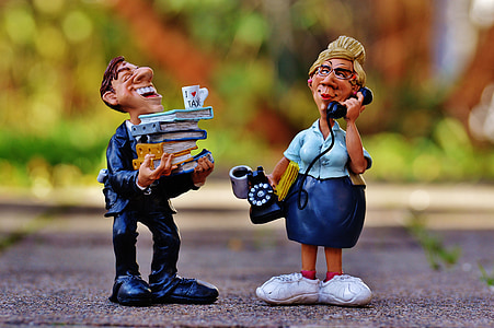 man holding books and woman using telephone figurines thumbnail