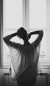woman standing beside window thumbnail