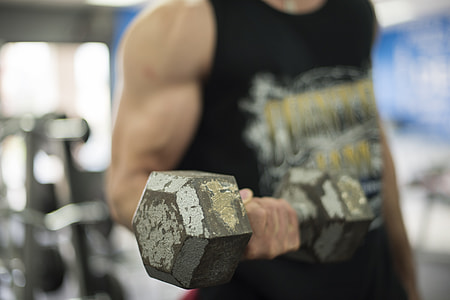 man in black and grey tank top lifting a grey hex-type dumbbell with his right hand thumbnail