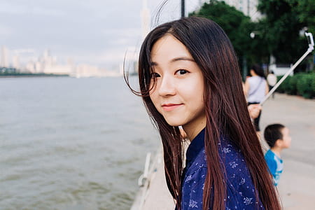woman wearing blue shirt standing near body of water thumbnail