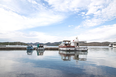 four docked speedboats under cirrus clouds and blue calm sky thumbnail