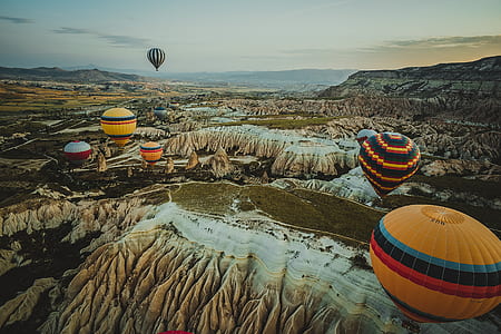hot air balloons flying over white and brown rock formations thumbnail