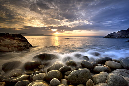 gray stones beside sea at daytime thumbnail