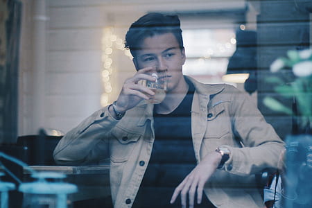 man in brown denim button-up jacket holding clear drinking glass thumbnail