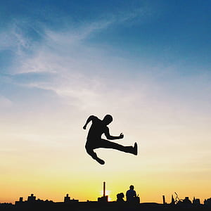 silhouette of man jumping near cityscape thumbnail