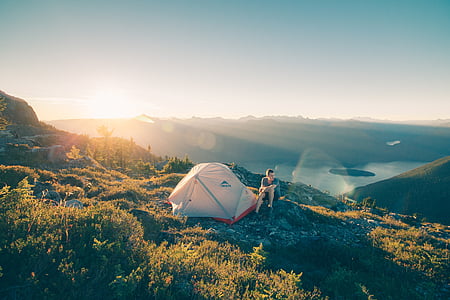 person sitting near tent on top of mountain thumbnail