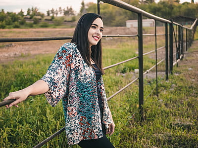 woman leaning on black metal fence smiling during daytime thumbnail