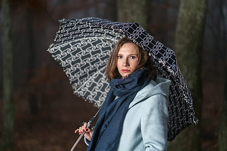 woman wearing black scarf and holding umbrella in front of gray wall thumbnail