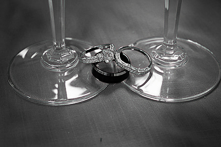 two silver-colored rings with clear gemstones on clear footed glass thumbnail