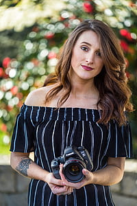 selective focus photography of woman holding Canon bridge camera during daytime thumbnail