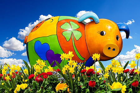 multicolored pig figurine on field of flowers thumbnail