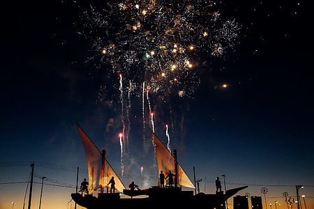 silhouette of people on boat watching fireworks display thumbnail