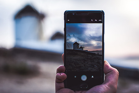 person holding smartphone displaying camera thumbnail