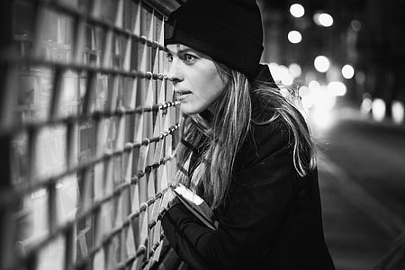 grayscale photo of woman looking through fence thumbnail