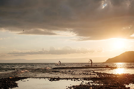 silhouette of two persons riding row boat thumbnail